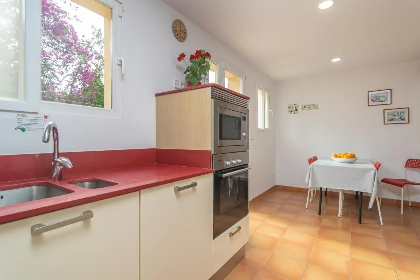 A bright kitchen with red countertops opens into a small dining area.