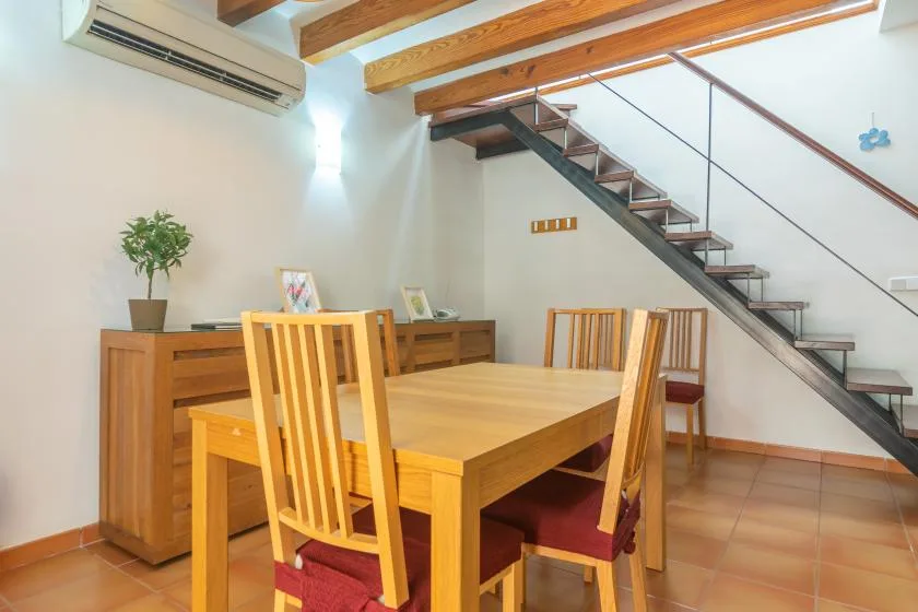 A dining area with a wooden table beneath an open staircase.