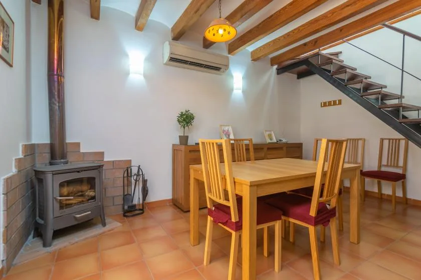 A dining area with a wooden table and chairs beside a fireplace and staircase.