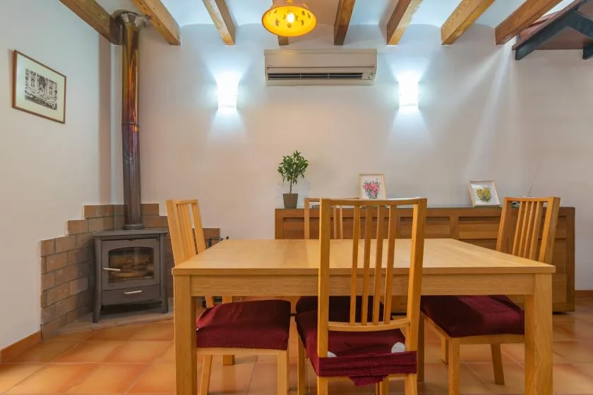 A dining area with a wooden table and chairs beneath exposed ceiling beams.