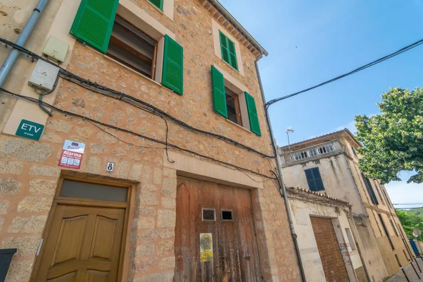 A stone building facade with green shutters and a wooden entrance.