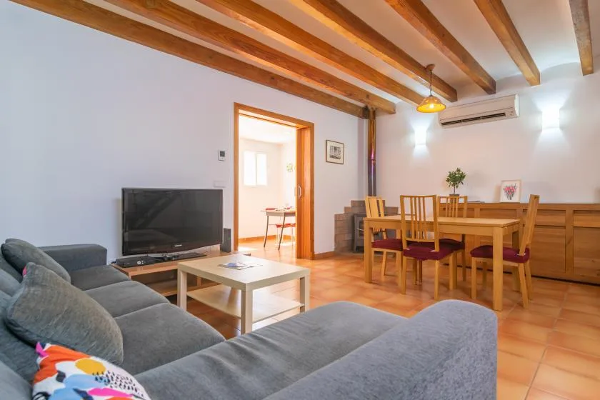 A living and dining area with seating, a television, and a wooden dining table.