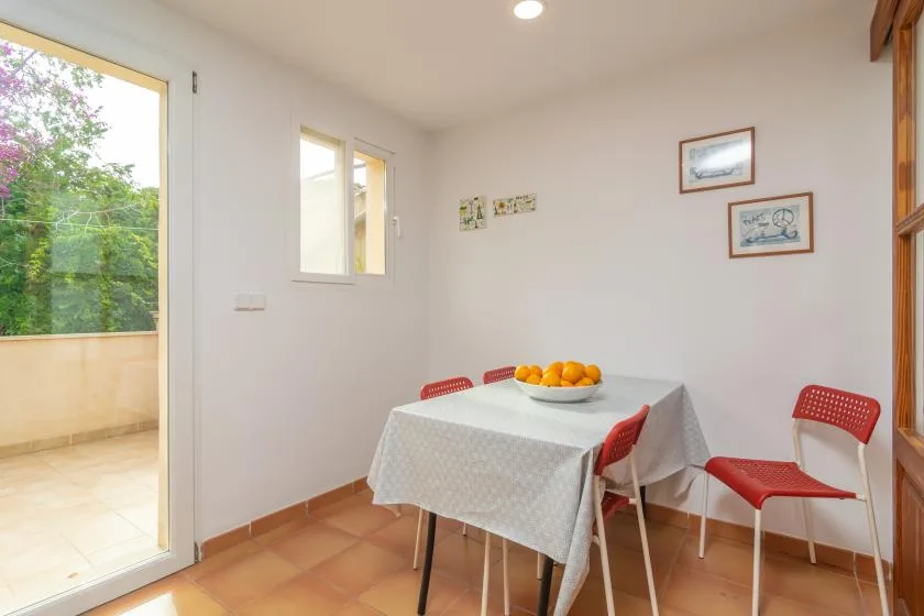 A dining area with a table set with a bowl of oranges and red seating.