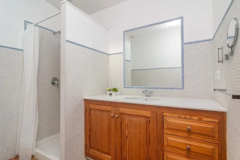 A bathroom with a wooden vanity, large mirror, and curtained shower.