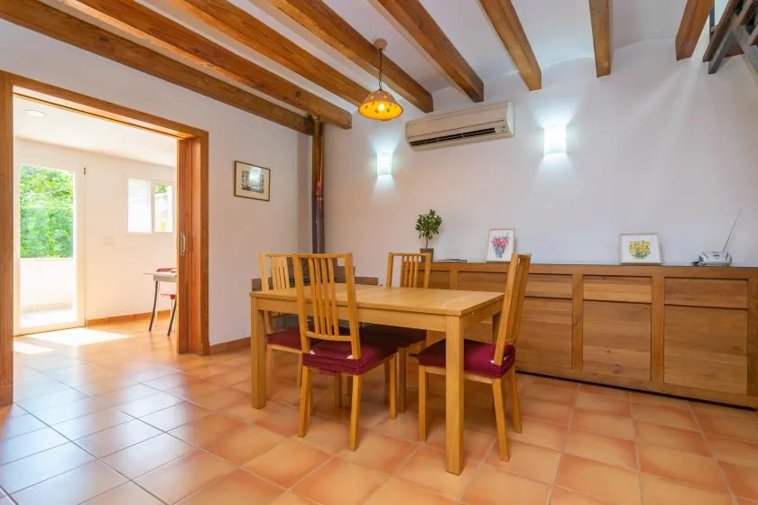 A dining area with a wooden table and chairs beneath exposed ceiling beams.
