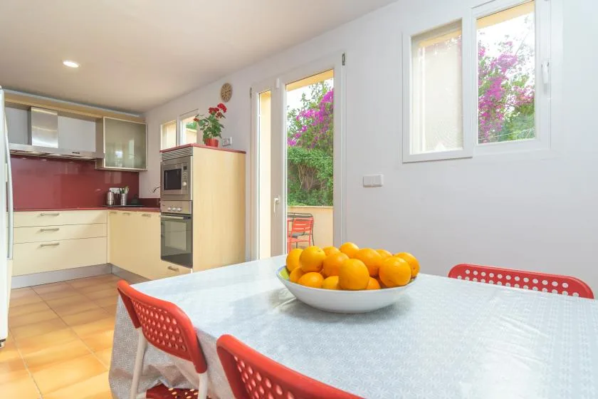 A bright kitchen and dining area with a bowl of oranges on the table.