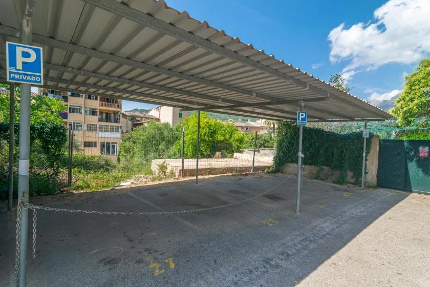 A covered parking area with painted spaces and greenery along the edge.