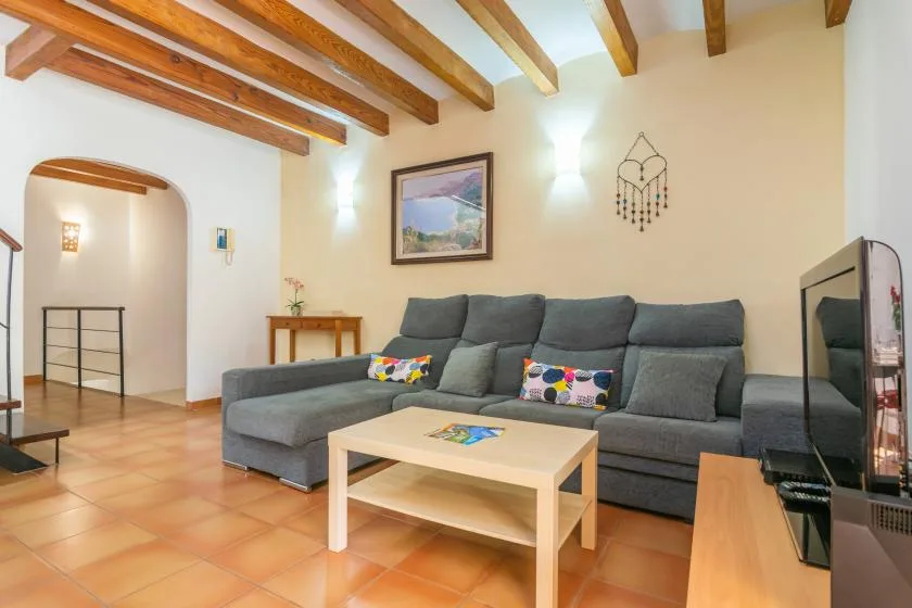 Living room with gray seating, a coffee table, and exposed ceiling beams.