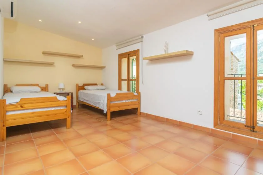 A bright bedroom with two single beds and large windows.