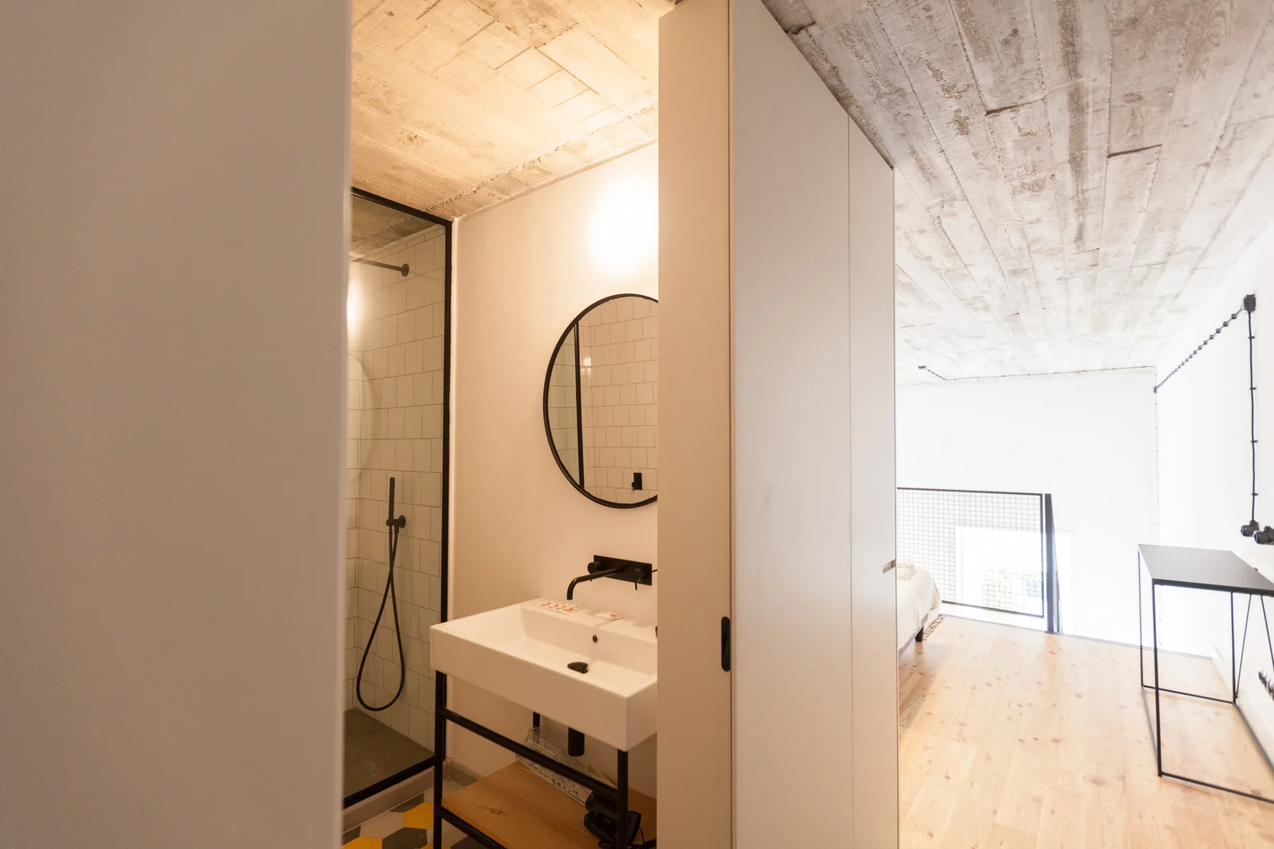 An open-plan room with a sink and shower beside a bright living area.