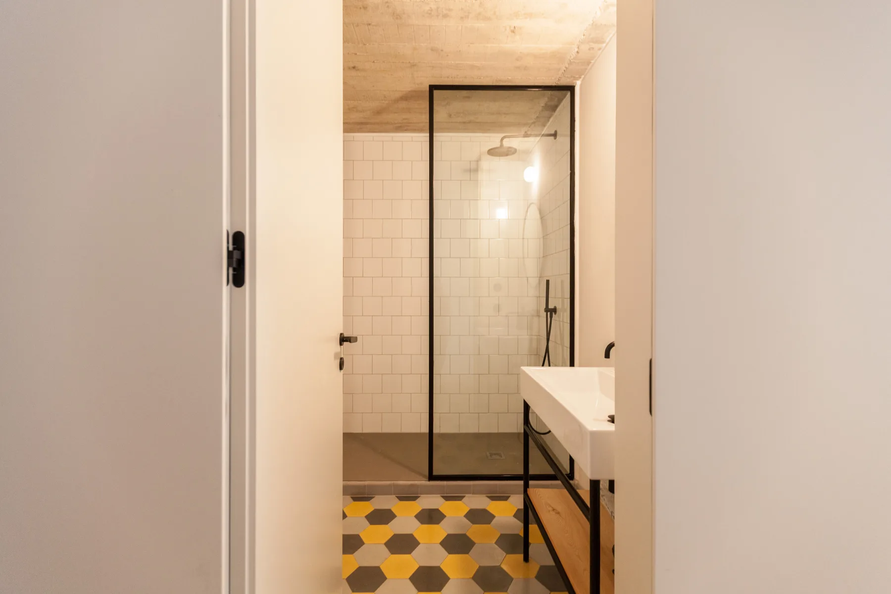 A bathroom with a glass shower and a patterned tile floor.