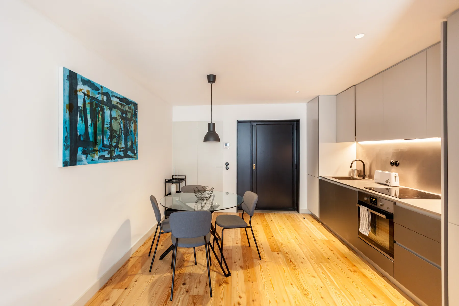 Una cocina moderna con zona de comedor, mesa, sillas y suelo de madera.