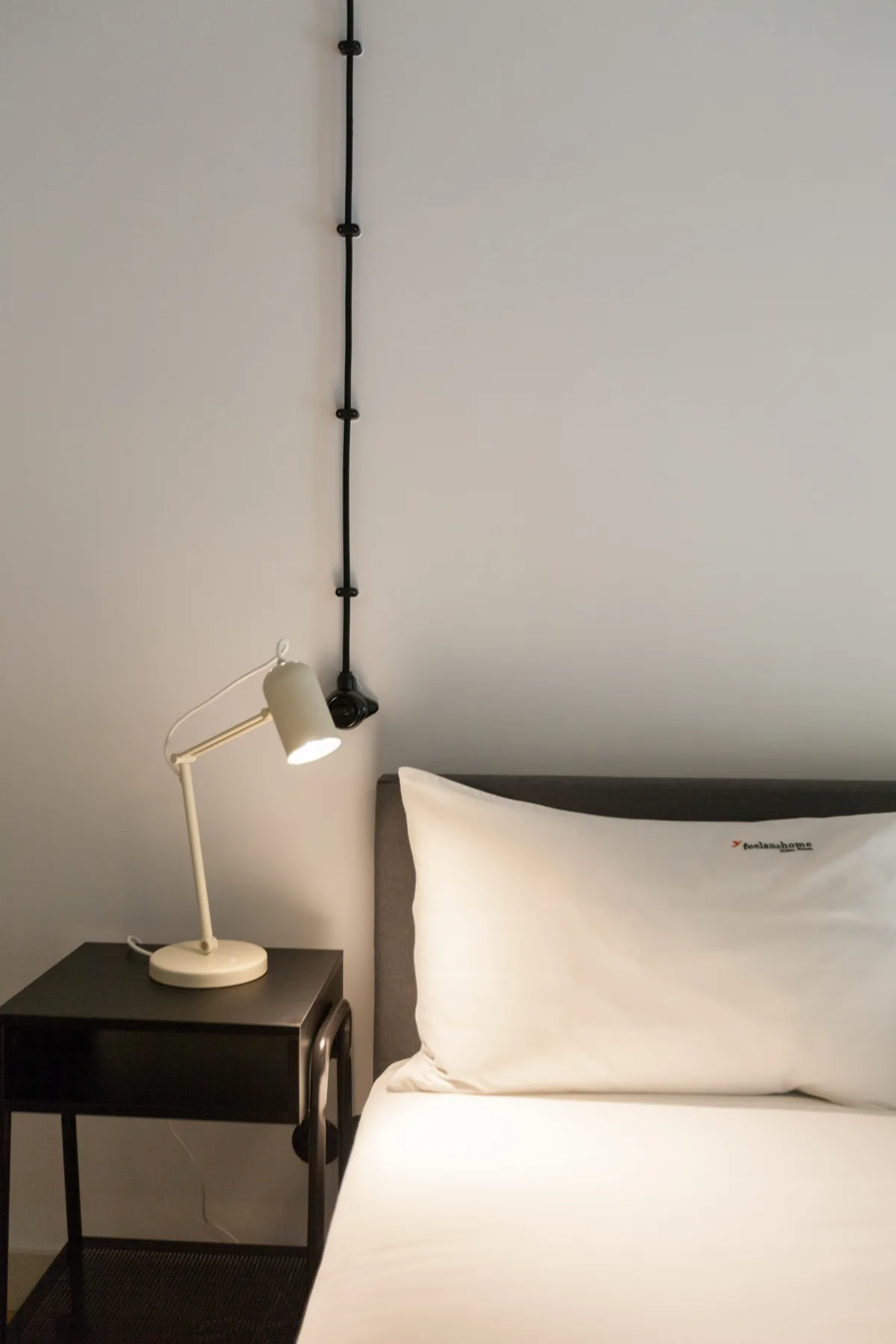 A bedroom with a neatly made bed and a bedside lamp.
