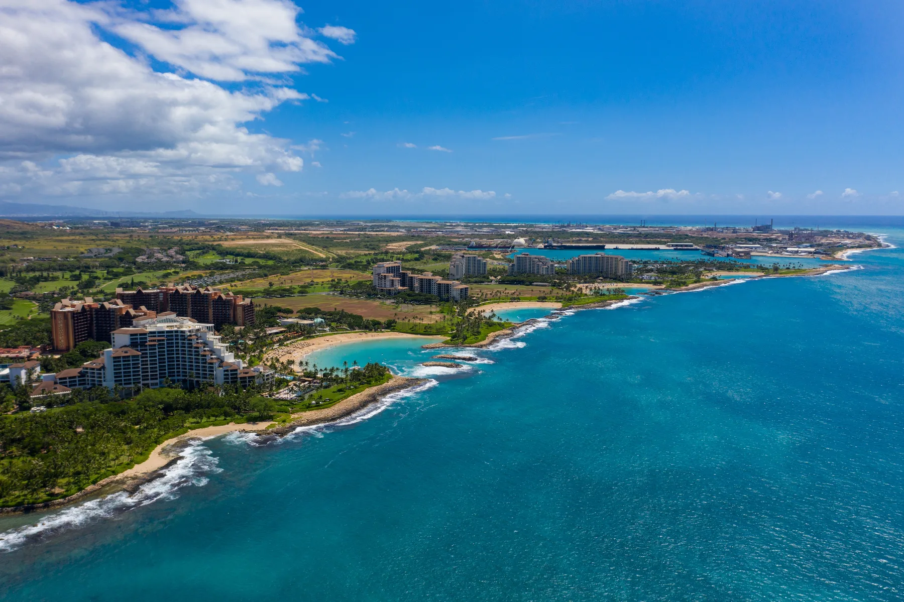 Vista aérea de aguas turquesas, costa arenosa y edificios turísticos.