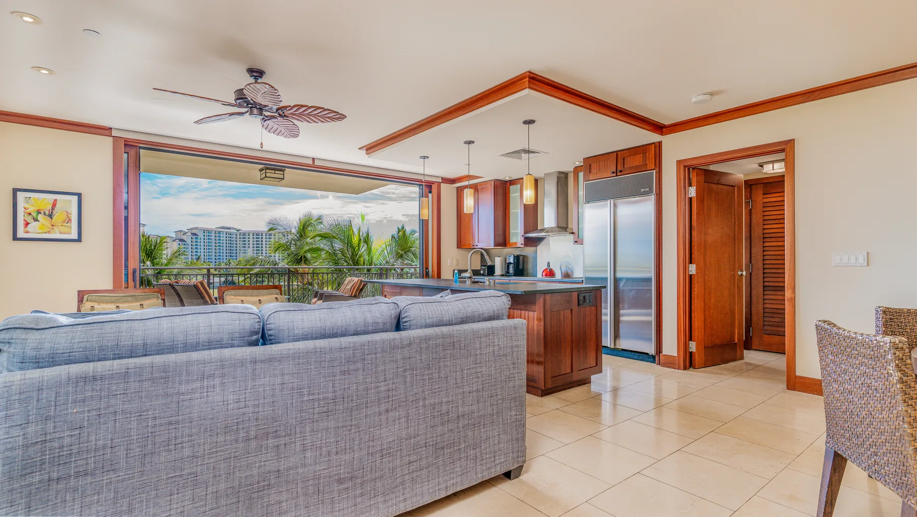 Una sala de estar con asientos, una cocina abierta y vistas por grandes ventanales.