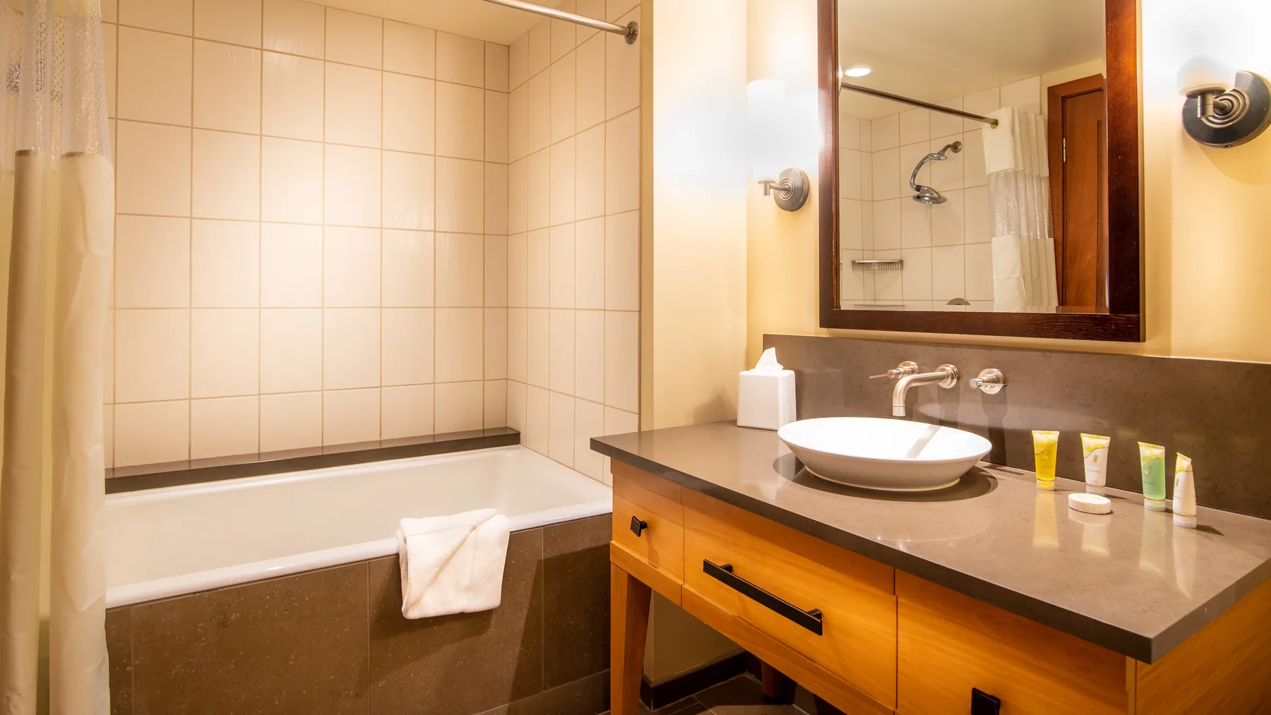 Un baño con bañera, tocador y un espejo grande en la pared.