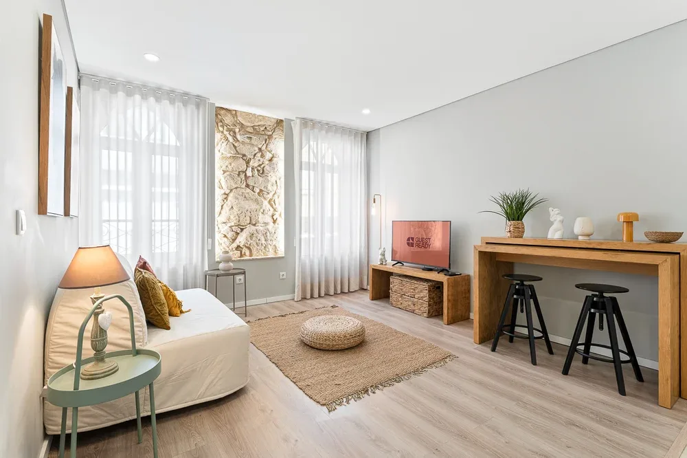 Bright living room with a seating area, television, and counter with stools.