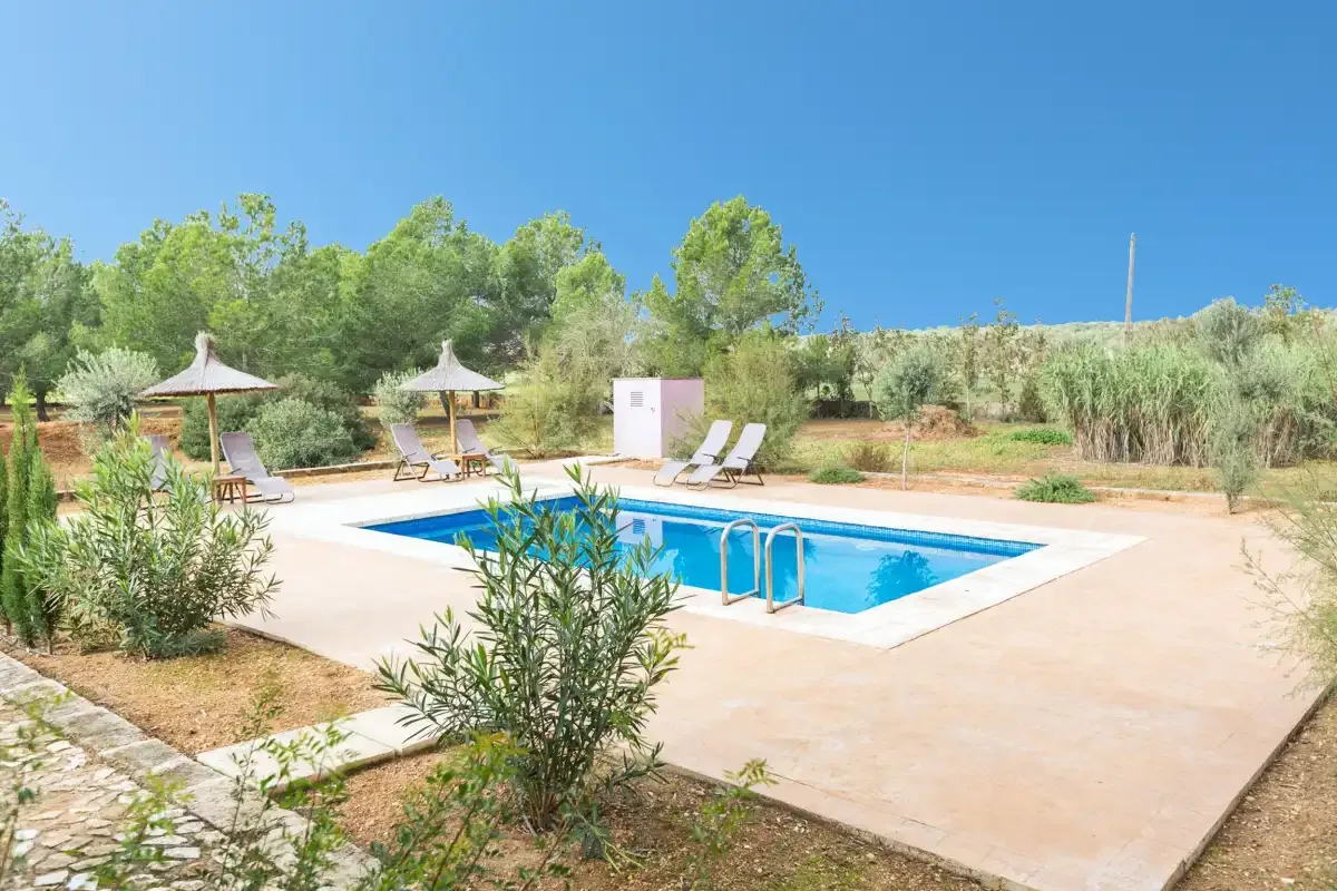 An outdoor swimming pool is surrounded by a paved terrace and lounge seating.