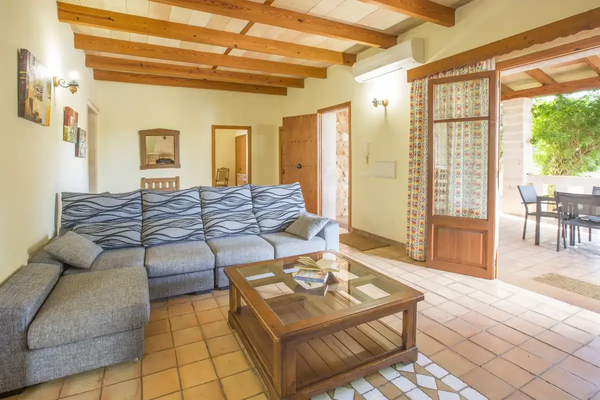 A living room with sectional seating and a wooden coffee table beside an open patio door.