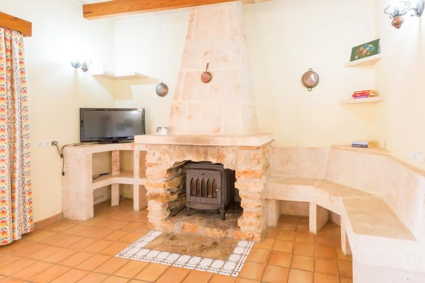 A living room with a stone fireplace, built-in seating, and a television.