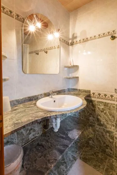 A tiled bathroom vanity has a white sink beneath a wall mirror.