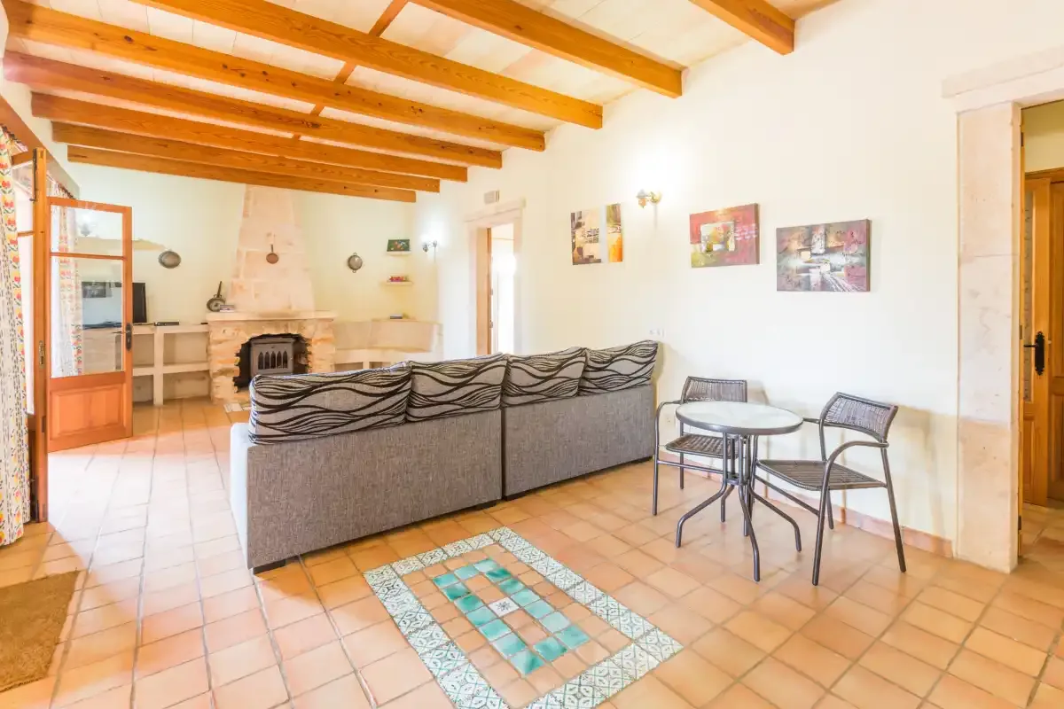 A living room with seating, a dining table, and exposed wooden ceiling beams.