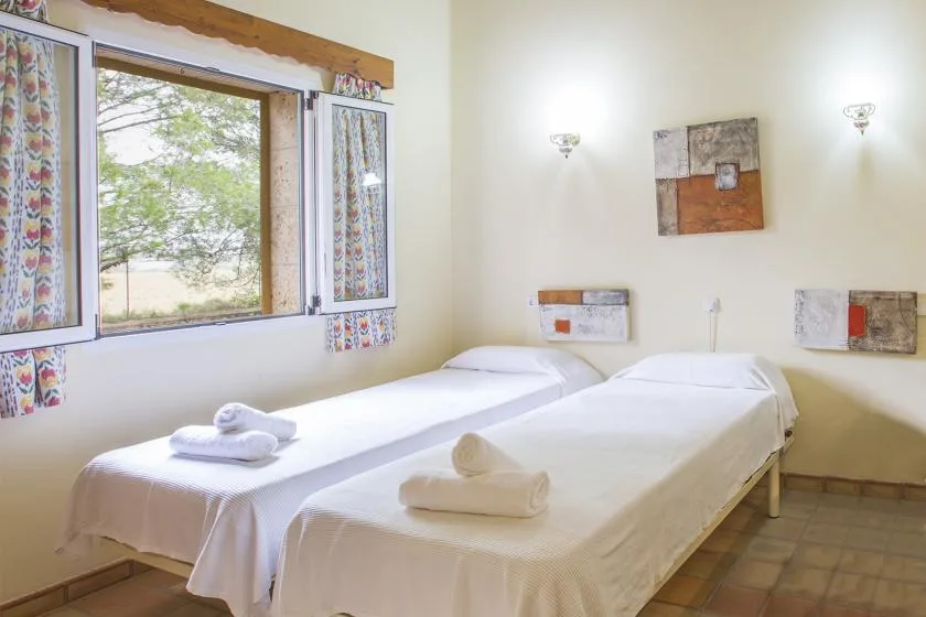 A bedroom with two single beds beside a window.