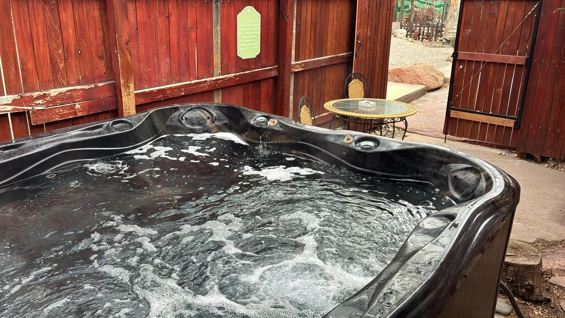 Jacuzzi negro en un patio junto a una cerca de madera