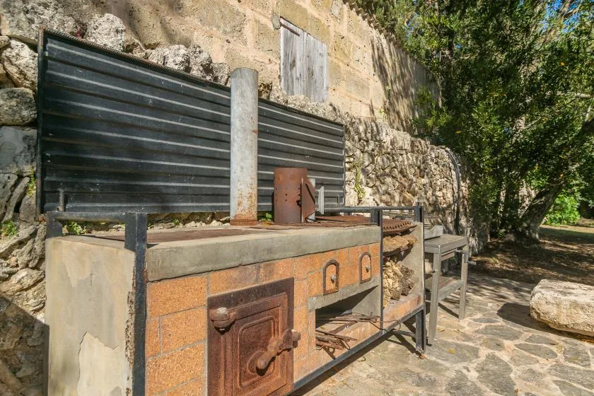 Una zona de cocina al aire libre con un horno de obra y una superficie de trabajo metálica.