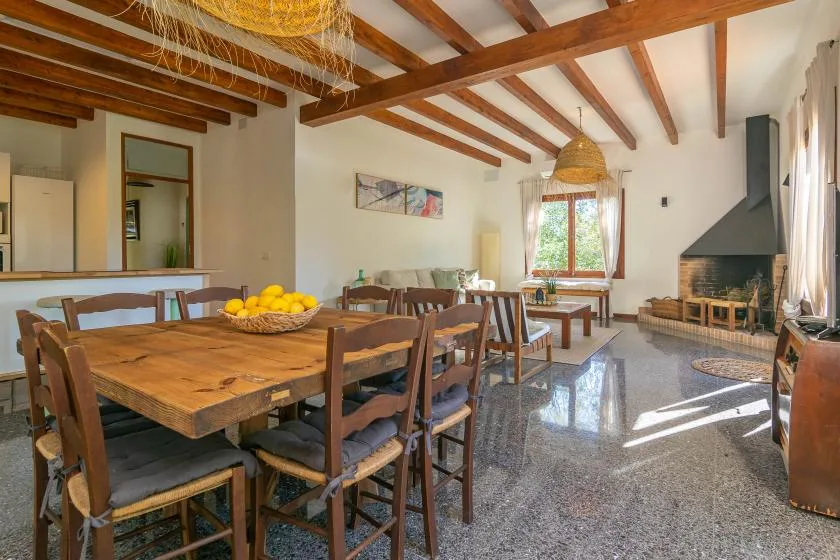 Una zona de comedor y estar con una mesa de madera y una chimenea.