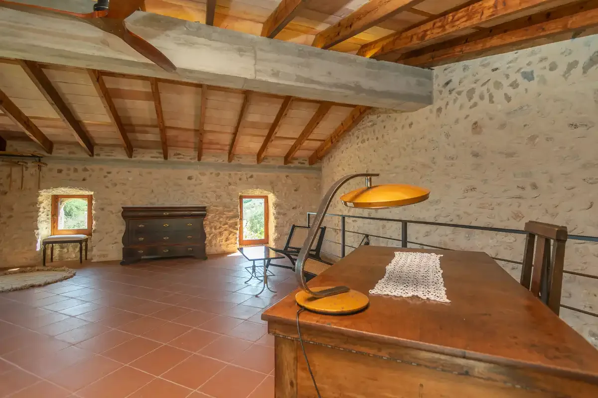 Una estancia rústica con una gran mesa de madera y vigas vistas en el techo.