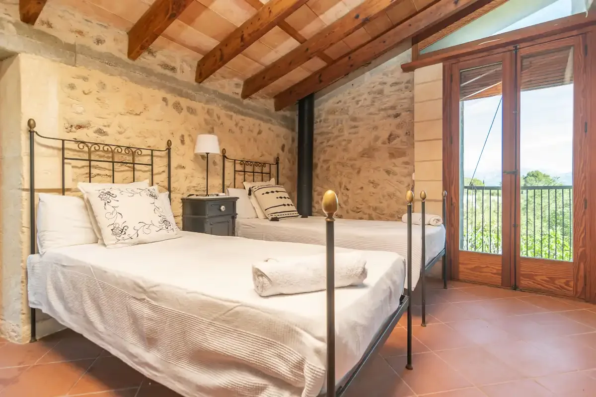 Un dormitorio con dos camas y puertas acristaladas que dan a un balcón.