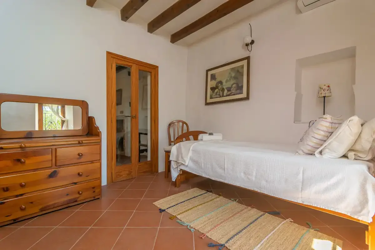 Un dormitorio con una cama doble, una cómoda de madera y vigas vistas.