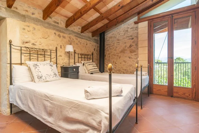 Un dormitorio con dos camas y puertas de cristal que dan a un balcón.