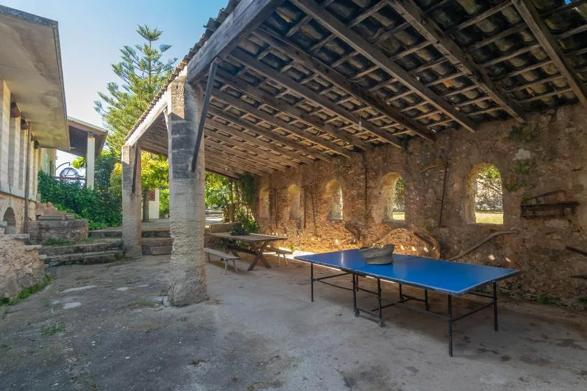 Un patio de piedra cubierto con una mesa de ping-pong azul y asientos de picnic.