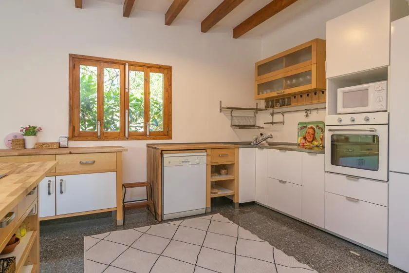Una cocina luminosa con gabinetes de madera, un fregadero y electrodomésticos integrados.