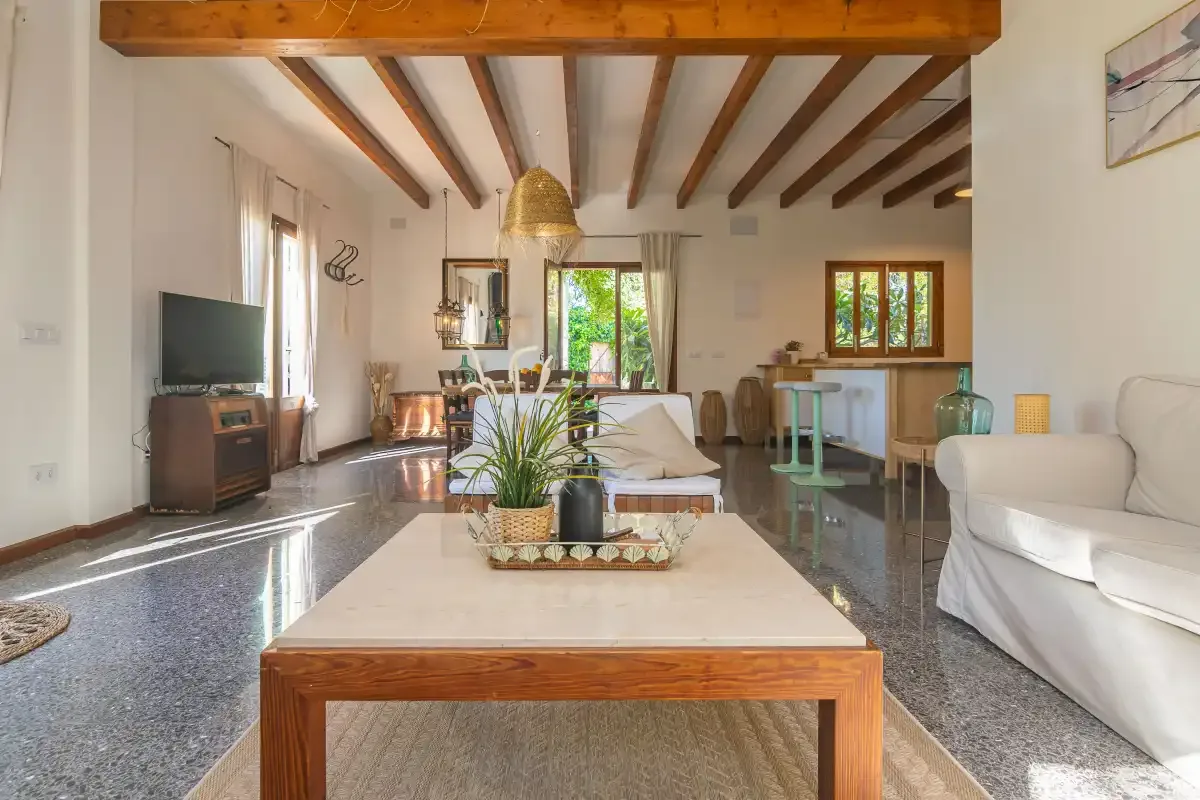 Una luminosa sala de estar con una mesa baja, asientos y vigas expuestas.