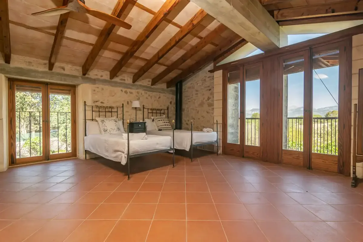 Un dormitorio con una cama y grandes ventanales que dan a un balcón.