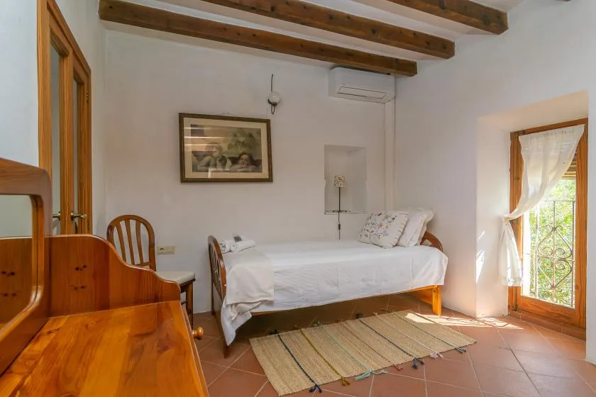 Un dormitorio con una cama, muebles de madera y una puerta de vidrio que da a un balcón.