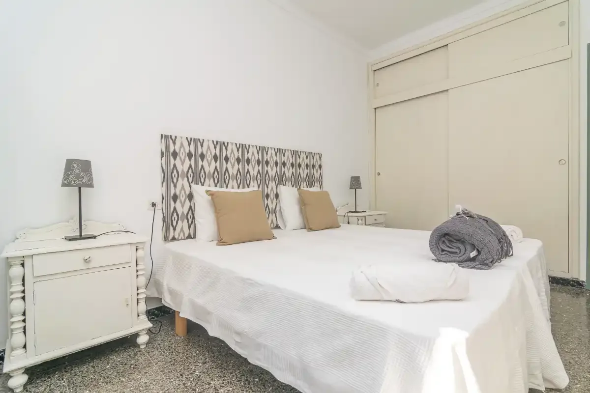 Un dormitorio luminoso con una cama bien hecha y un cabecero estampado.