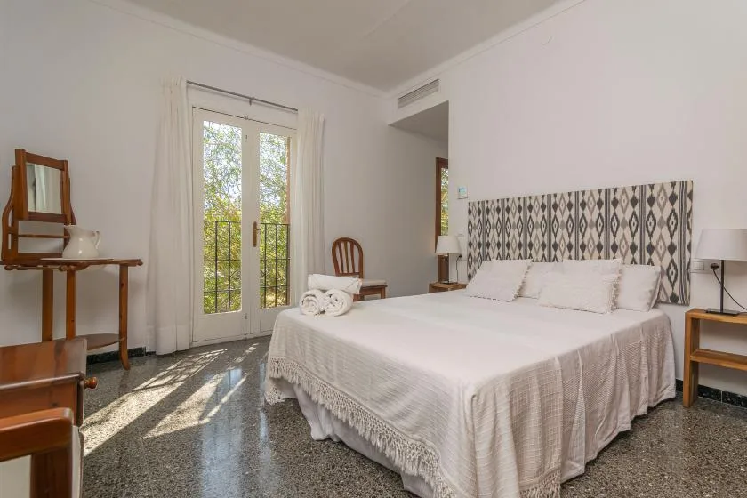 Un dormitorio luminoso con una cama grande y puertas acristaladas que dan a un balcón.