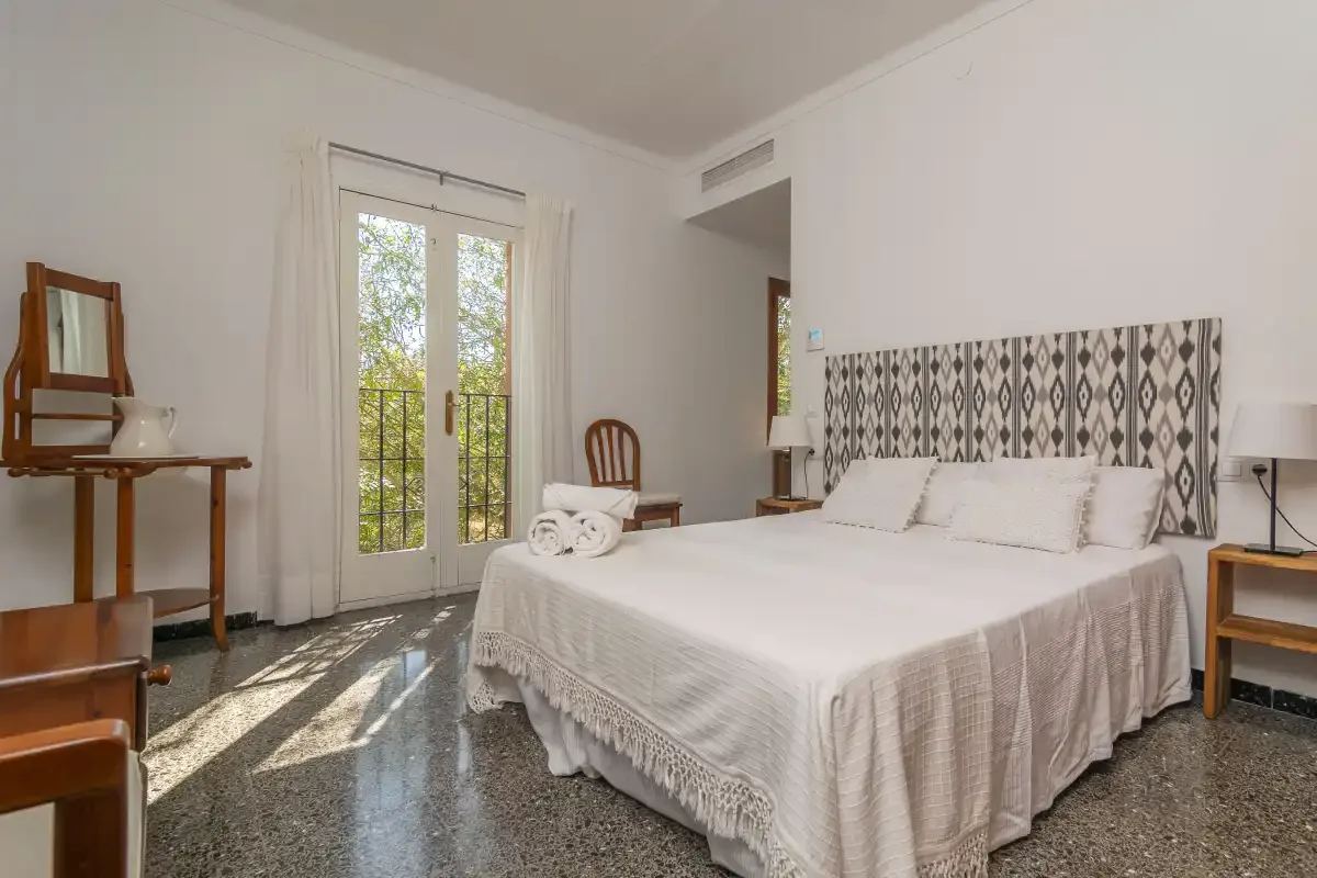 Un dormitorio luminoso con una cama grande y puertas acristaladas altas.