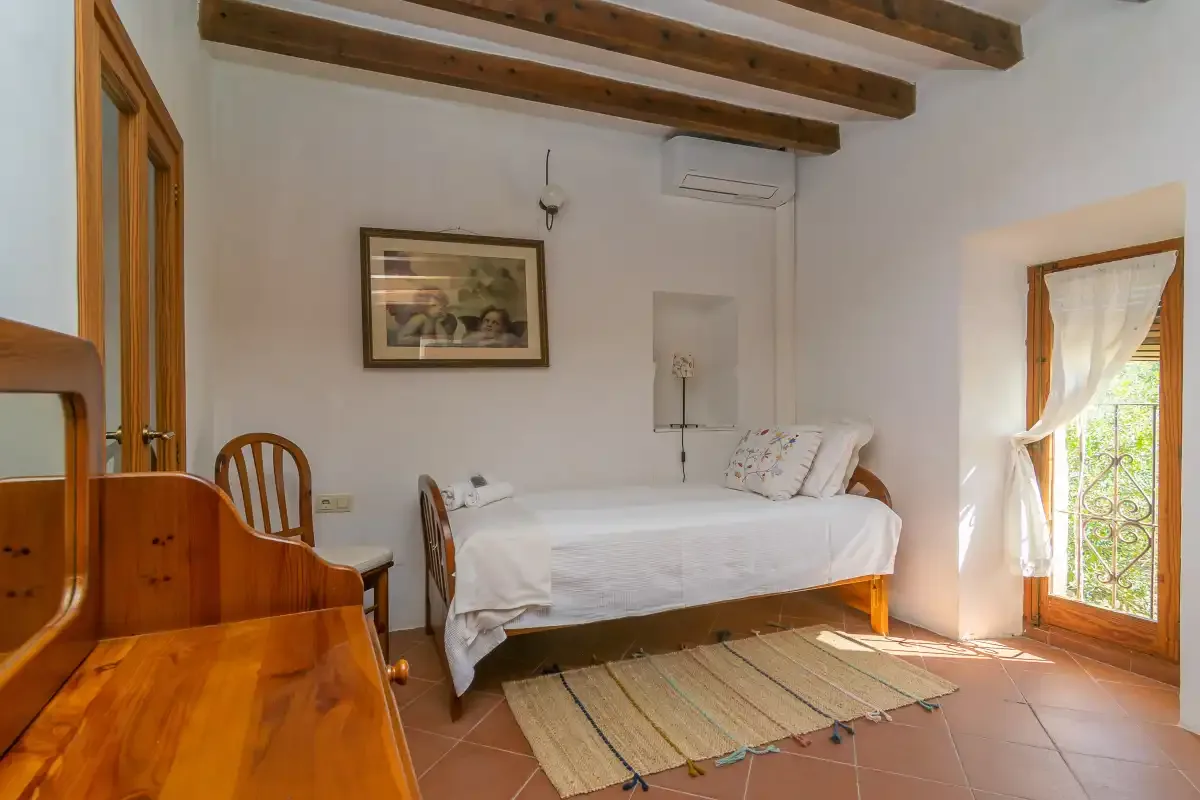 Un dormitorio con una cama, muebles de madera y una puerta acristalada que da a un balcón.