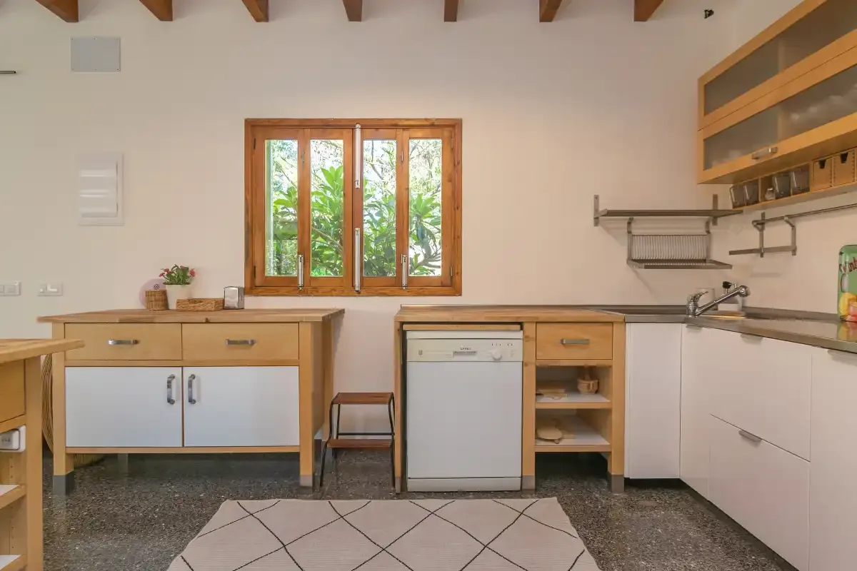 Una cocina luminosa con armarios de madera y una ventana con vistas a la vegetación.
