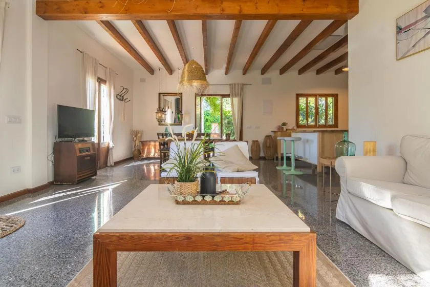 Una sala luminosa con mesa de centro, asientos y vigas expuestas en el techo.