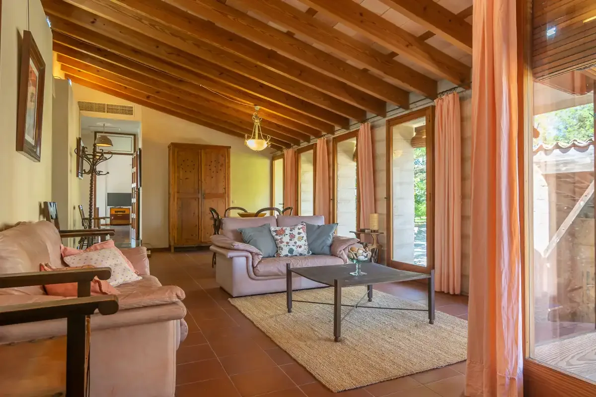 Una sala de estar con asientos alrededor de una mesa de centro junto a grandes ventanas.