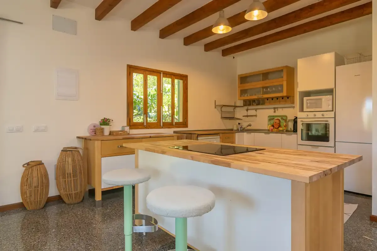 Una cocina luminosa con vigas de madera en el techo y una isla central alargada.