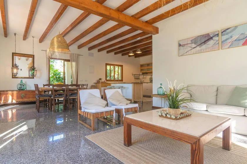 Una sala-comedor abierta con asientos, una mesa de comedor y vigas de madera a la vista.