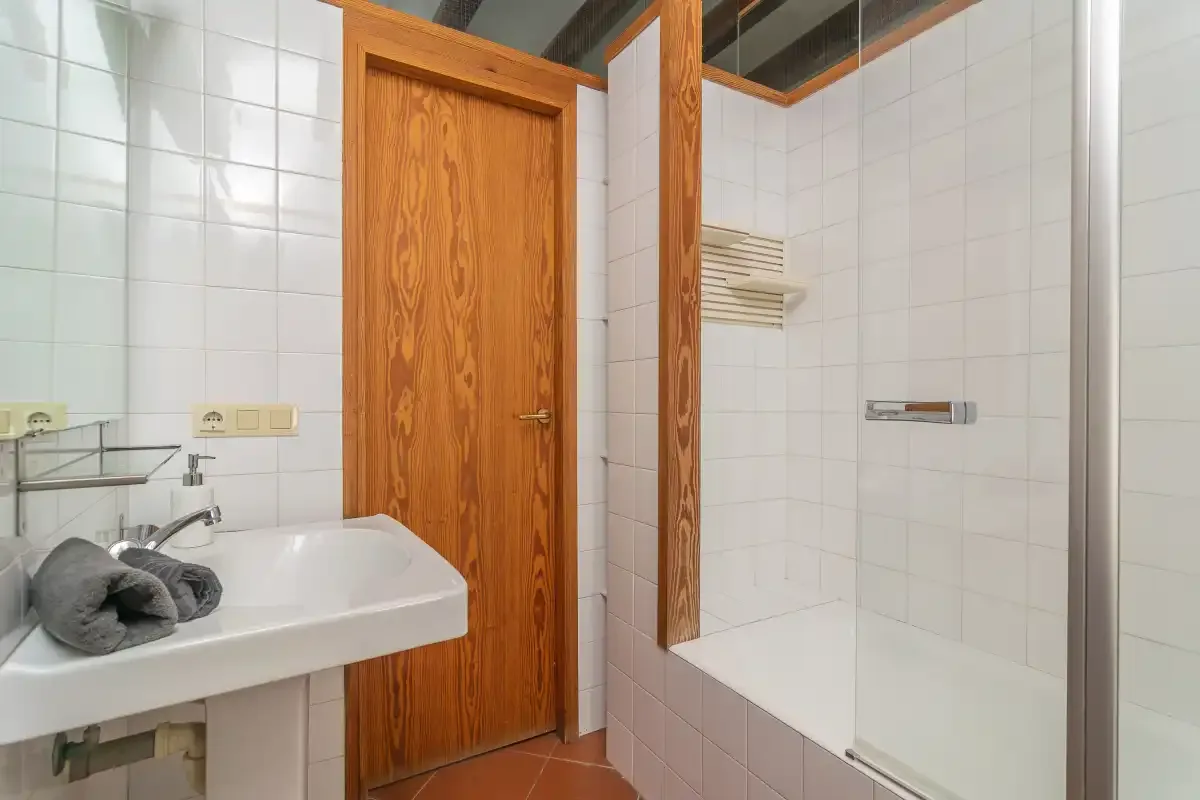 Un baño alicatado con un lavabo y una ducha con mampara de vidrio.