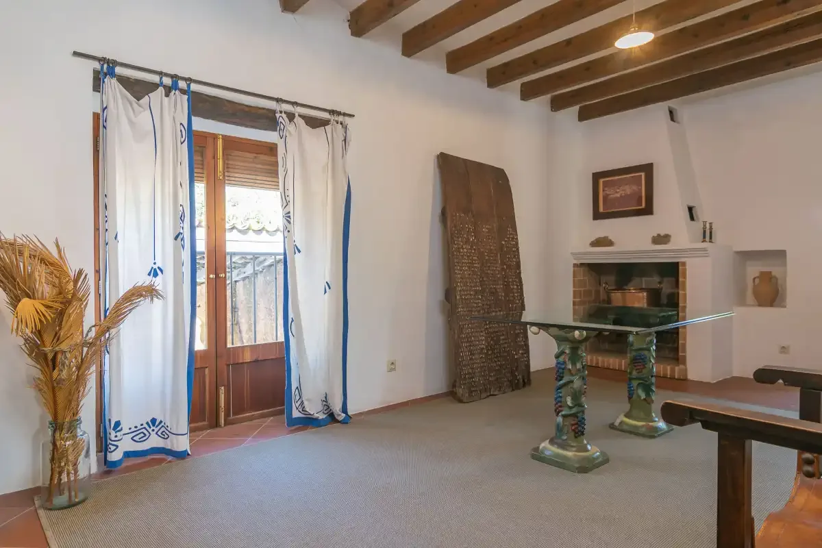 Una sala de estar con una mesa de vidrio y vigas de madera a la vista.